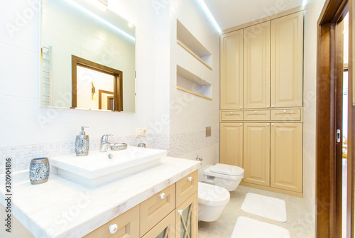 bathroom with elegant rectangular washbasin  toilet and shower. Mirror with light on top. The white tile.