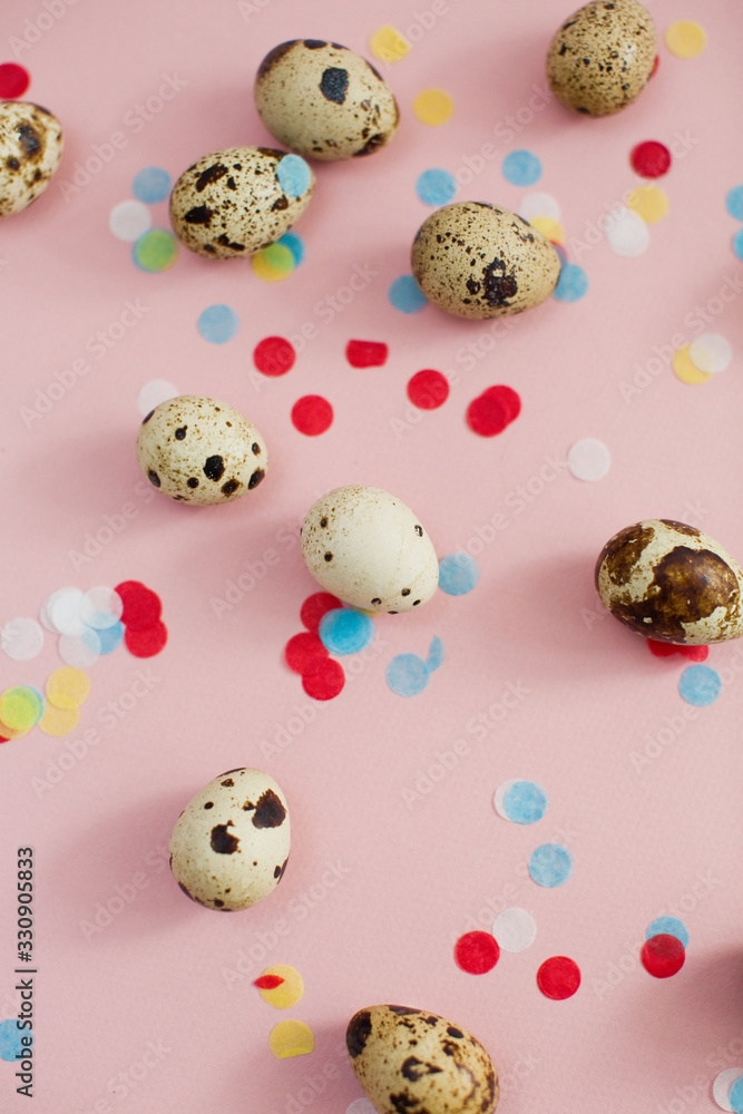 Quail eggs on a pink background with colorful confetti Quail eggs on a pink background with colorful confetti