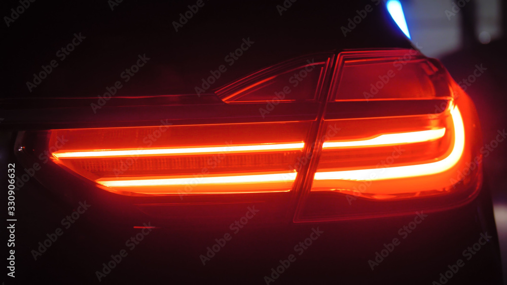 Adaptive taillights optics of a luxury car on a dark background