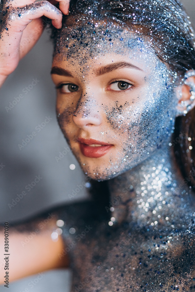 Close up portrait of young fashionable model with art make up with blue sparkles. Fashion, art, beauty concept