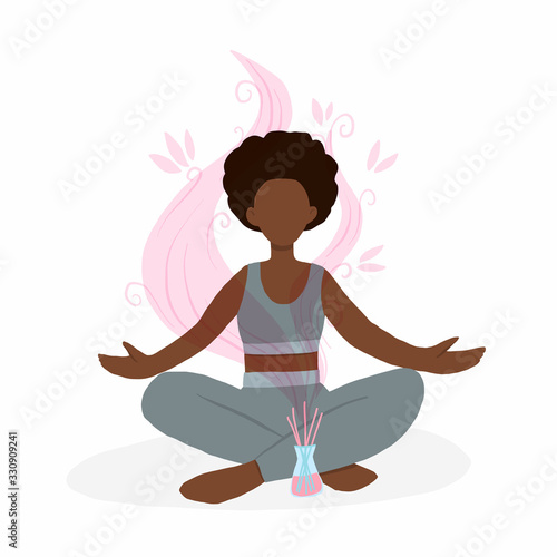 Young african american woman sitting in lotus pose with aroma diffuser. Aromatherapy and relax. Self care at home.