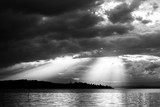 Sunrays at near sunset, with dark clouds in the background, above Trasimeno lake (Umbria, Italy)
