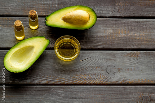 Avocado oil for cosmetology. Sltill lfe with half of fruit and bottles on wooden background copy space photo