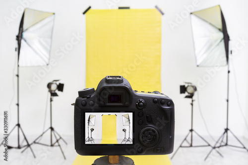 Camera in a photo studio with yellow backdrop and light equipment photo