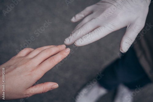 Two hands of a couple, one in a plastic glove, reaching each other. Virus protection concept, health issues. Closeup