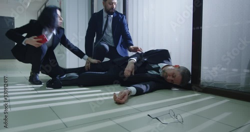 Coworkers helping unconscious manager in office photo