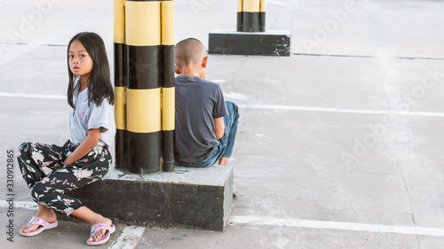 Asian girls and boys waiting for their parents at the mall parking lot.