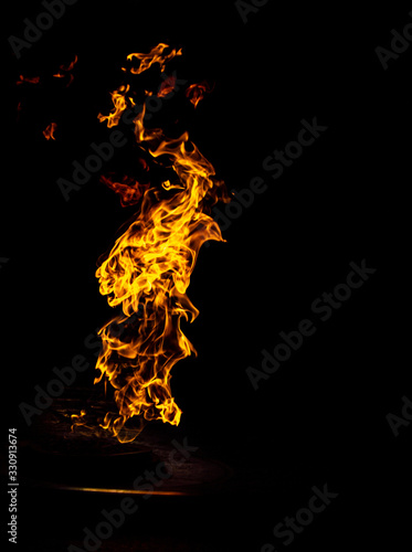 Bright flame in a metal bowl on a black background © Alexandr