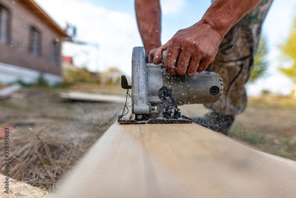 A worker saws a wooden beam.
