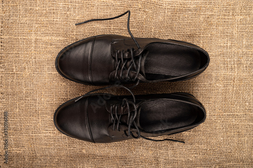 A pair of black leather boots with lacing on a background of coarse fabric. Close up. photo