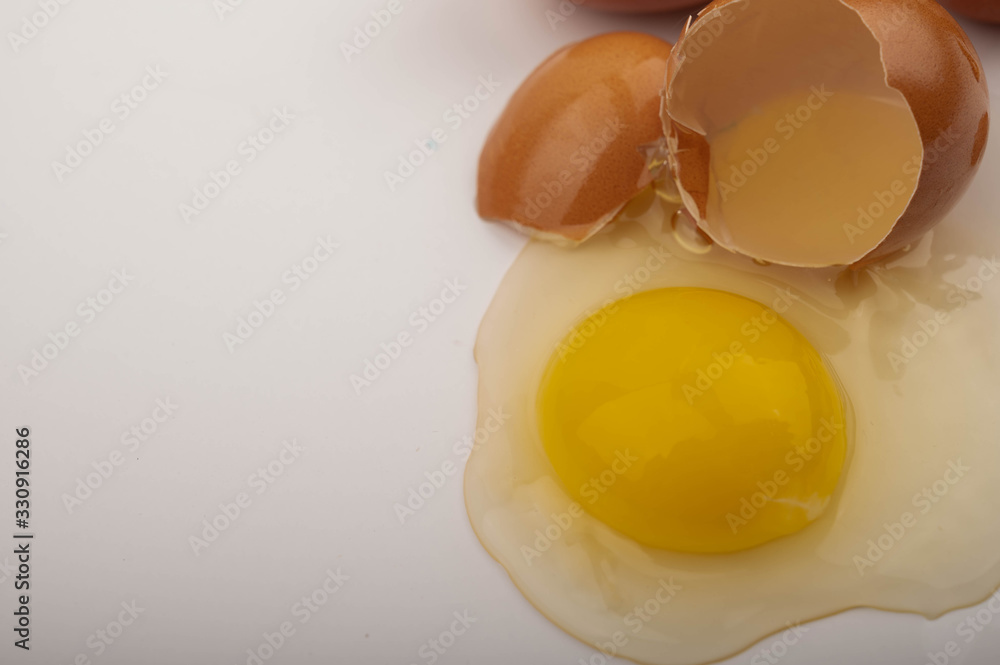 A broken chicken egg on a white background. Close up. A broken chicken egg on a white background. Close up.