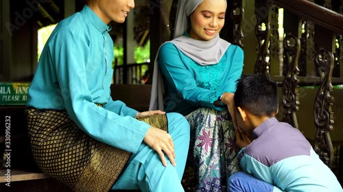 boy greeting to malay couple sitting on stair way