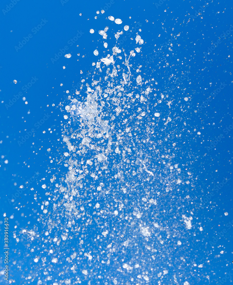 Splashing water from a fountain on a background of blue sky