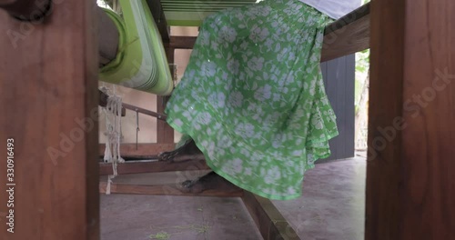 A footage of a woman using loom in a traditional asaian factory photo