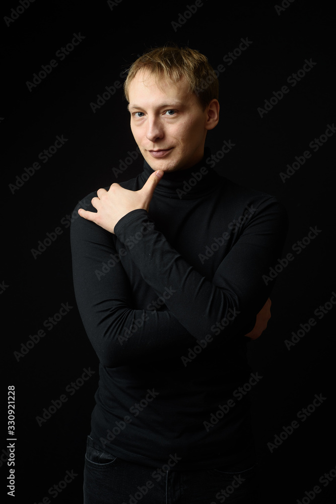 Portrait of determined goodlooking man wearing black shirt, black background.