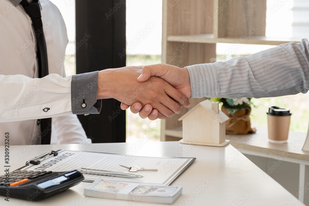 Businessmen and brokers real estate agents catch hand after completing negotiations to buy houses insurance and sign contracts. Home insurance concept Businessmen and brokers real estate agents catch hand after completing negotiations to buy houses insurance and sign contracts. Home insurance concept