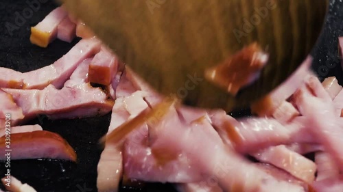 Finely chopped ham is fried in hot oil in a pan.
