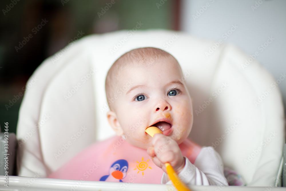 Portrait Of Happy Young Baby girl In High Chair. Baby eating Portrait Of Happy Young Baby girl In High Chair. Baby eating