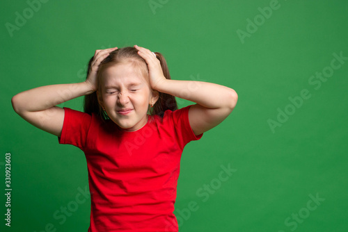 Headache. brunette girl in red t-shirt clutching head and grimacing in terrible pain on green background