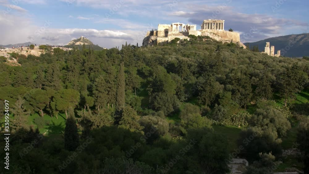The Parthenon of the Acropolis of Athens and Lycabettus hill in the background, surrounded by olive trees, wide shot The Parthenon of the Acropolis of Athens and Lycabettus hill in the background, surrounded by olive trees, wide shot