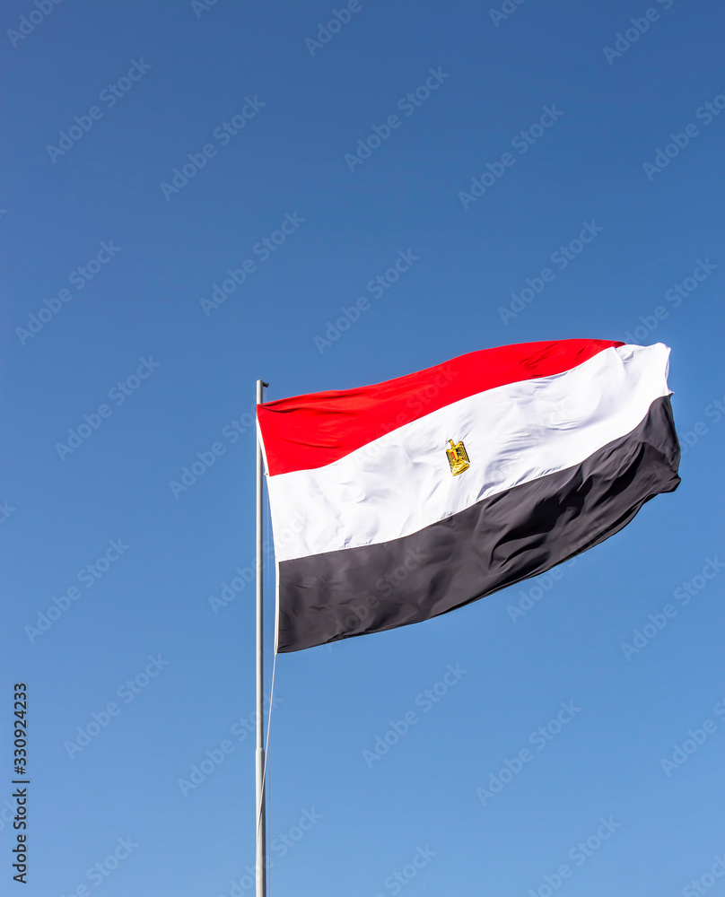 National flag of Egypt flying high against the blue sky National flag of Egypt flying high against the blue sky