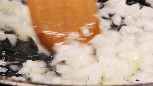 Close up shot of finely chopped onion fried in oil in a pan.