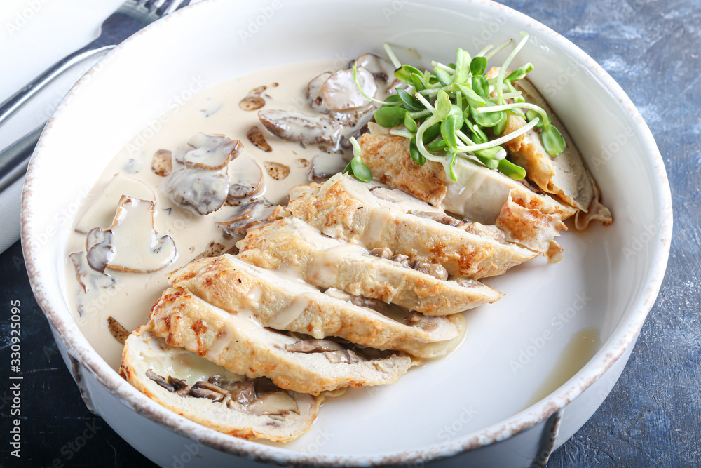 Chicken breast roll with mushrooms. Next to the champignon sauce. On a dark background. Decorated with microgreen. Chicken breast roll with mushrooms. Next to the champignon sauce. On a dark background. Decorated with microgreen.