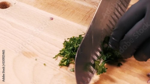 Slicing fresh parsley on a large cutting board with a large knife