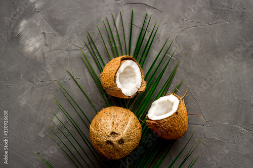Coconuts and leaves - tropical still life on grey background top-down