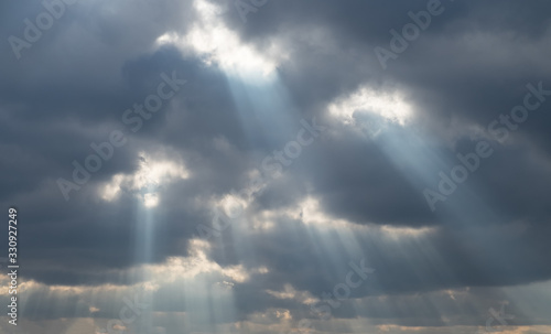 The blue rays of the sun through the grey clouds. Extraordinary view of the sky. Holes in the clouds © VLADISLAV