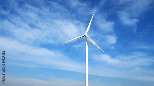 Wind turbine against cloudy blue sky background