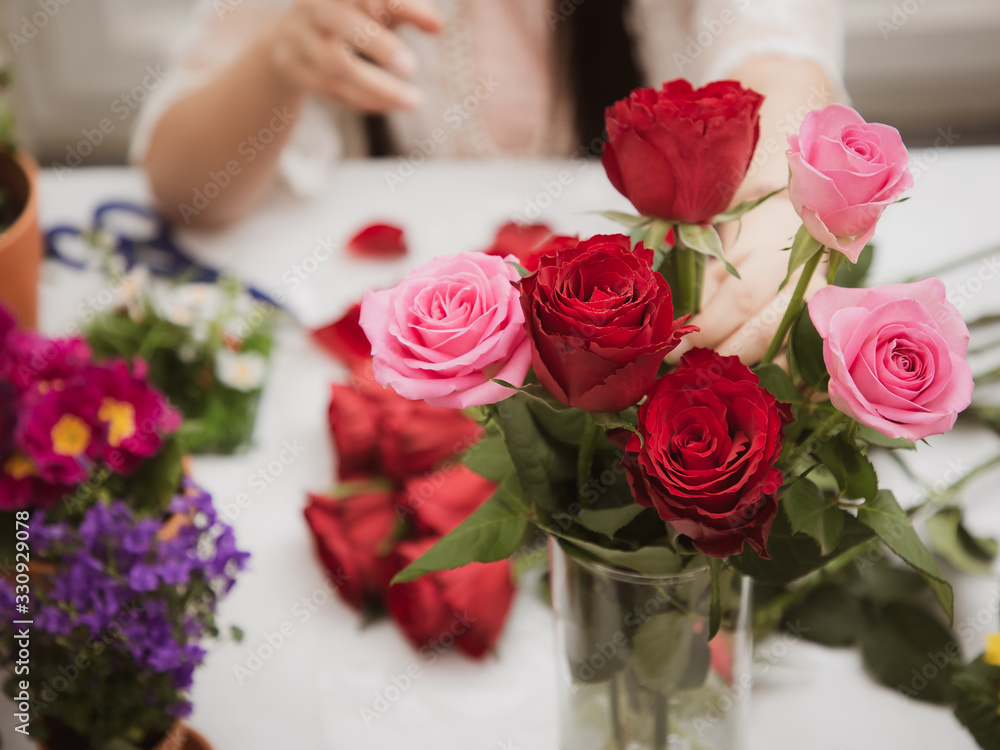 Woman Preparing to trim red and pink roses and beautiful flower arrangements in the home, flower arrangements with vase for gift-giving for Valentine's Day and Business in the family on the on table Woman Preparing to trim red and pink roses and beautiful flower arrangements in the home, flower arrangements with vase for gift-giving for Valentine's Day and Business in the family on the on table