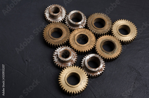 Pyramid structure made of different gears on the balck background.Closeup of metal parts of engine as a symbol of teamwork and growth