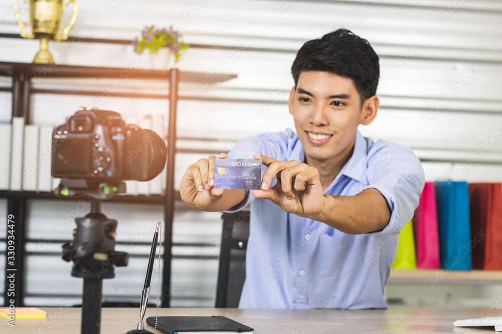 Young Asian influencer reviews credit card while recording a video. Young Asian influencer reviews credit card while recording a video.
