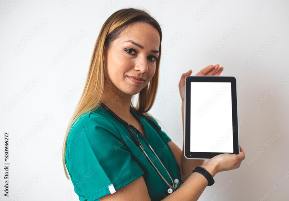 Smiling young nurse pointing at tablet with blank screen isolated on white Smiling young nurse pointing at tablet with blank screen isolated on white