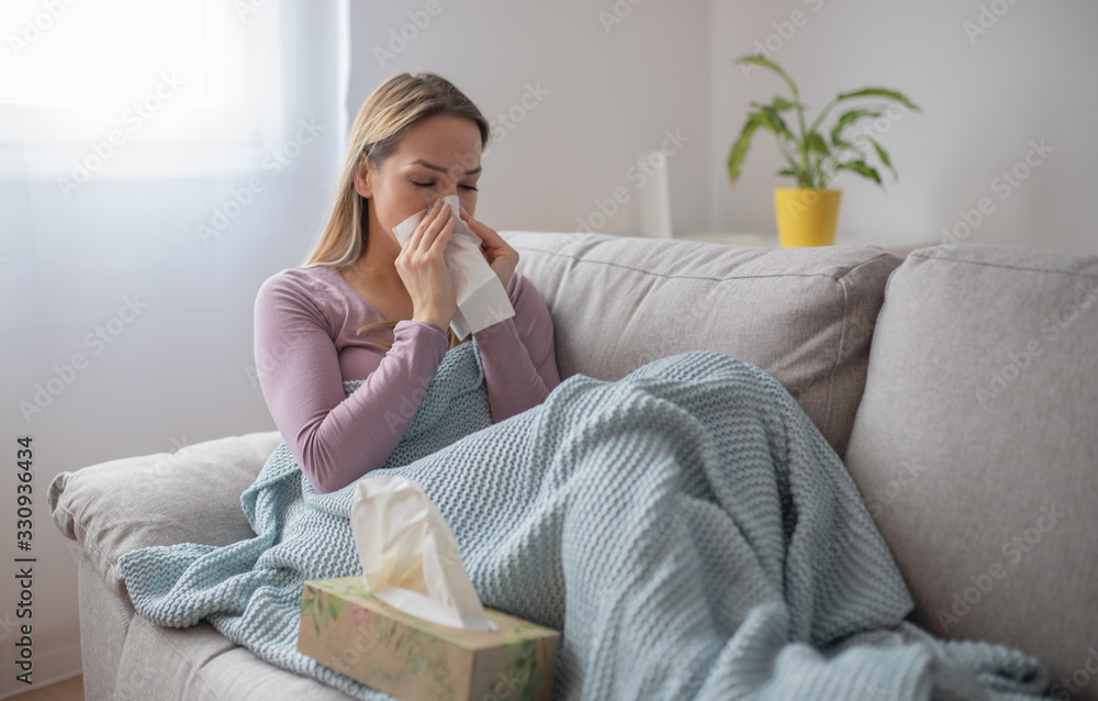 Sick woman blowing nose, sitting under the blanket. Sick woman with seasonal infections, flu, allergy lying in bed. Sick woman covered with a blanket lying in bed with high fever and a flu, resting. Sick woman blowing nose, sitting under the blanket. Sick woman with seasonal infections, flu, allergy lying in bed. Sick woman covered with a blanket lying in bed with high fever and a flu, resting.