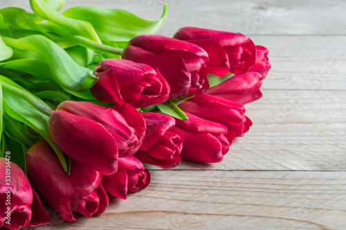 Festive greeting card with bouquet of blooming red tulips. Spring background with copy space.