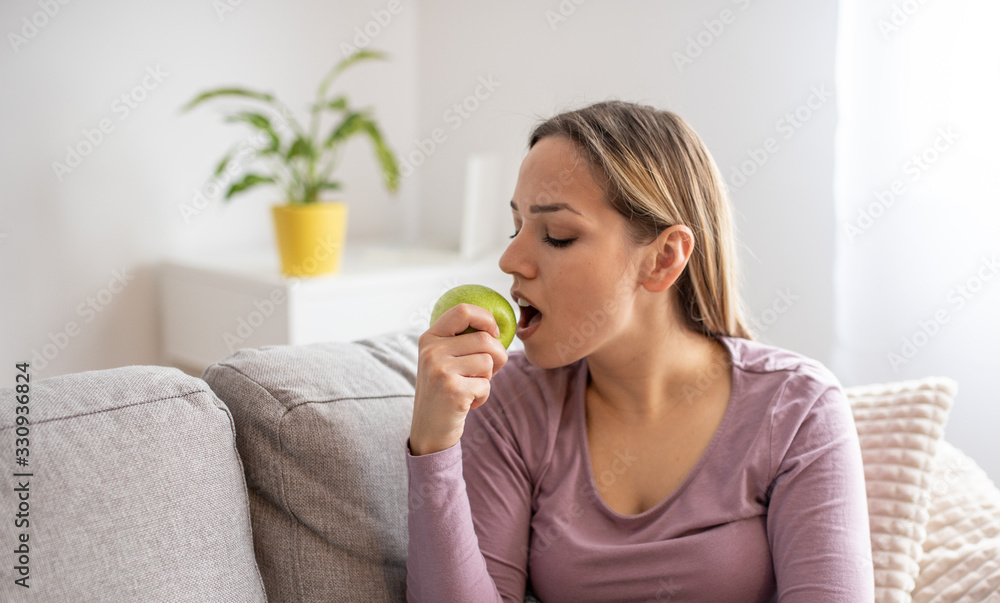 Young attractive woman sitting in sofa, eating apple. Healthy life concept Young attractive woman sitting in sofa, eating apple. Healthy life concept