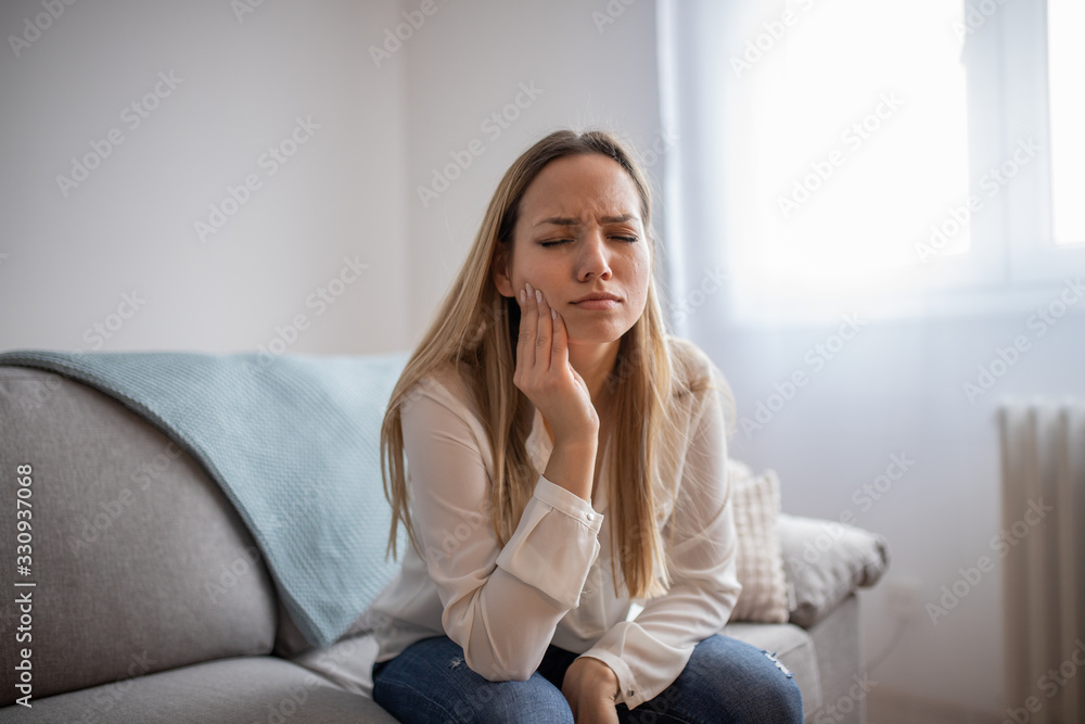 Attractive young woman suffering from toothache. Woman holding her cheek in pain Attractive young woman suffering from toothache. Woman holding her cheek in pain