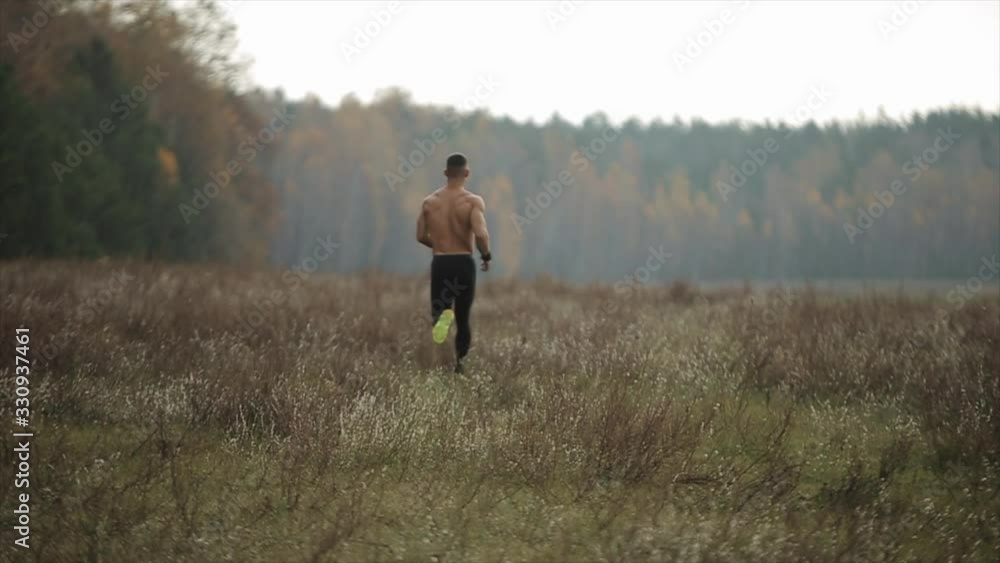 Muscular man with naked torso running across the field. Slow motion Muscular man with naked torso running across the field. Slow motion