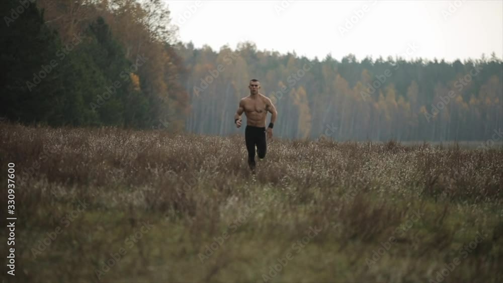 Muscular man with naked torso running across the field. Front view Muscular man with naked torso running across the field. Front view