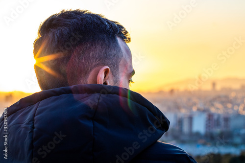 an alone man looking though a city skyline at a beautiful sunset and thinking. photo