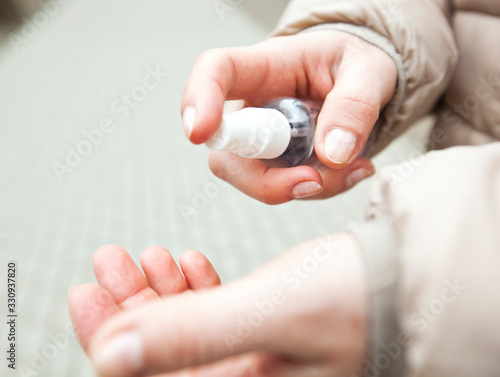 The young woman sanitizing her hand by sanitizer