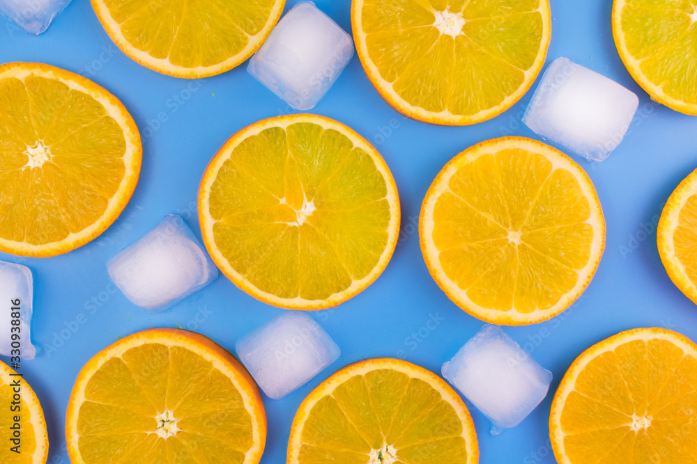 Slices of orange and ice cubes on a blue background.Summer background. Slices of orange and ice cubes on a blue background.Summer background.