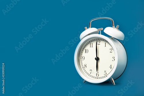 White alarm clock on a blue background. Place for text