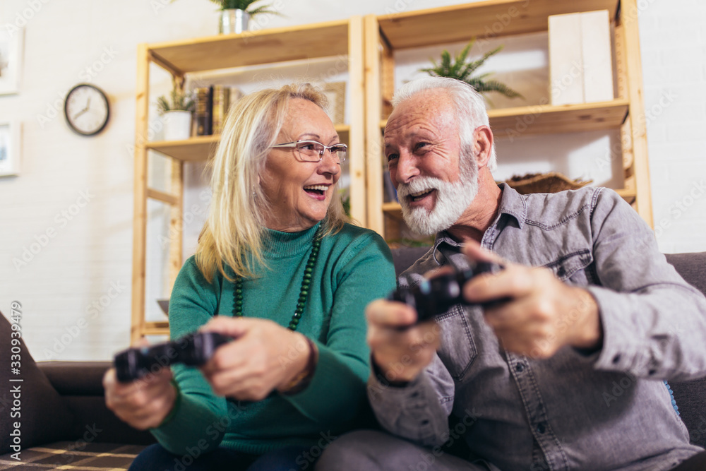 Senior couple having fun at home playing video game holding joysticks in hands.Quarantine. Senior couple having fun at home playing video game holding joysticks in hands.Quarantine.