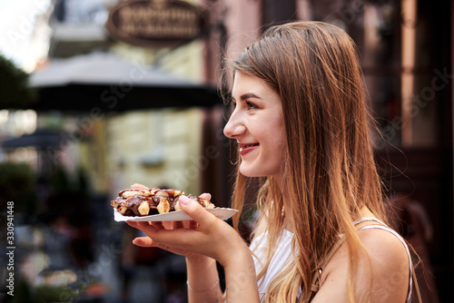 Romantic couple on date eating tasty belgian waffle with chocolate and caramel. Young blond woman  feeding brunette man with yummy desert in summer in the morning. Nutritious breakfast  snack.