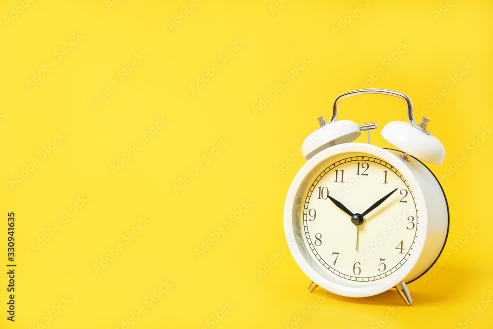 White alarm clock on a yellow background. Place for text White alarm clock on a yellow background. Place for text