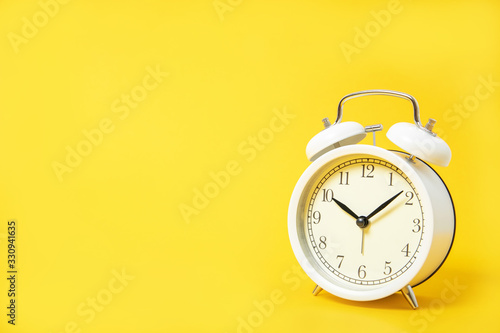 White alarm clock on a yellow background. Place for text