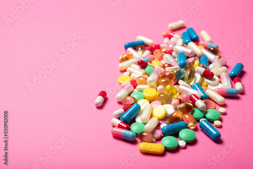 Pills and capsules on a pink background.Concept of medicine and health.